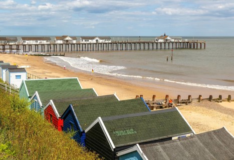 View over beach huts to sandy beach and pier, Southwold, Suffolk, England, UK