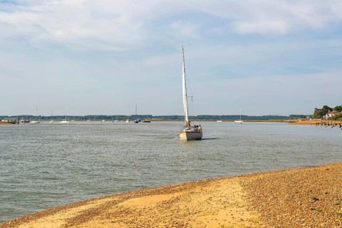 Sailing boat yacht at mouth of River Deben estuary, Bawdsey Quay, Suffolk, England, UK