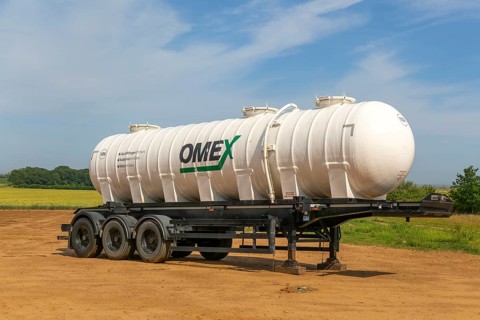 Omex fertiliser road tanker container waggon standing in field, Alderton, Suffolk, England, UK