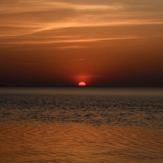 Atmospheric sunset... Cuxhaven, North Sea, in calm weather, glowing red sun sinking into the sea,