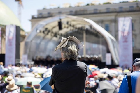 A visitor protects himself from the sun with a newspaper on his head at the Staatsoper für alle, a