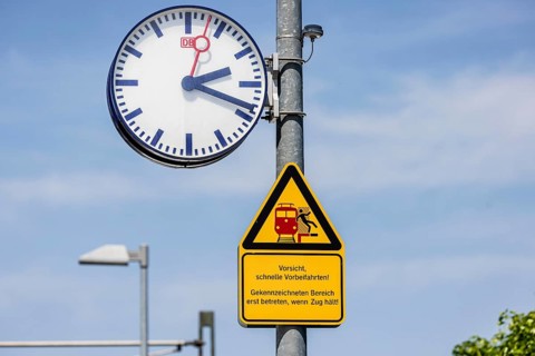 Platform with signs, station clock and warning sign Caution, fast passing. Karlsruhe,
