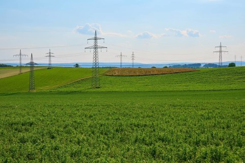 Extensive green fields with electricity pylons and a blue sky with clouds, Marktheidenfeld,