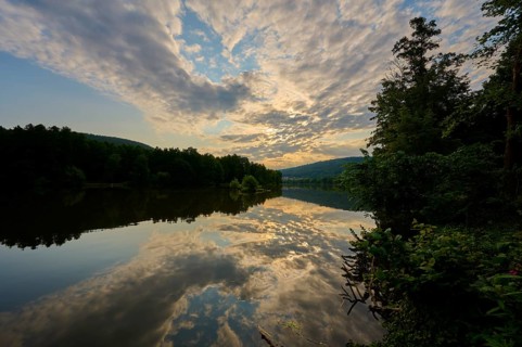 A quiet river with dramatic sky and clouds in the golden light of sunrise, summer, Grünenwört,