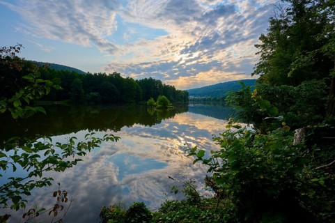 A dramatic sky reflected in a quiet river, surrounded by lush trees, summer, Grünenwört, Wertheim,