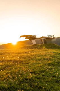 Sunset over a green meadow with a silhouette of a cable car station, Alpe di Siusi, Dolomites,