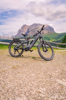 An e-bike stands on a gravel path in front of a mountain landscape, Alpe di Siusi, Dolomites, South
