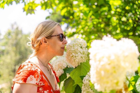 Woman in a red dress smelling a white flower, surrounded by green plants, Botanical Garden, The