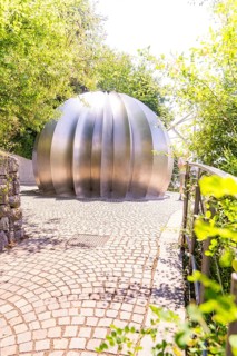 Modern metal sculpture in a sunny park with green foliage in the background, Botanical Garden, The