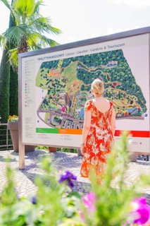 Woman in orange dress looking at a large map in a garden, Botanical Garden, The Gardens of