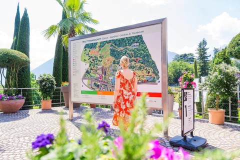 Woman in front of an information board in a sunny garden area, Botanical Garden, The Gardens of