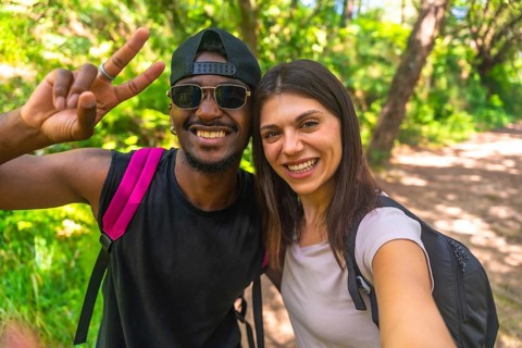 Smiling hikers capturing a selfie while enjoying their adventure on a bright, sunny day in the lush