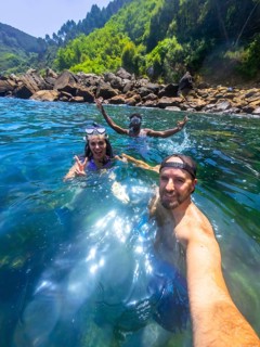 Three friends enjoy snorkeling in the refreshing ocean water, capturing a selfie moment amidst a