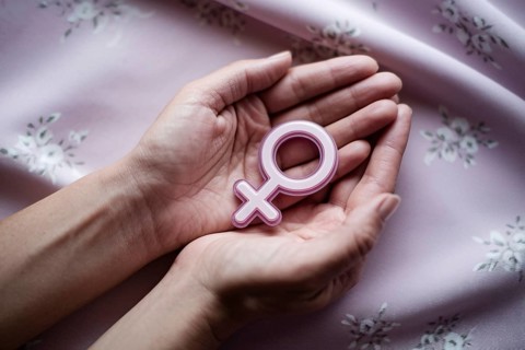 Woman's hands cradling glossy female gender symbol. A visual tribute to strength, femininity, and