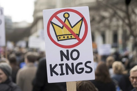 Close-up of protest sign with text No kings and crossed-out crown. Demonstration in progress.