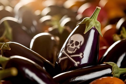 Skull-carved eggplant warns of hidden toxins or pesticides in fresh produce at farmer's market.