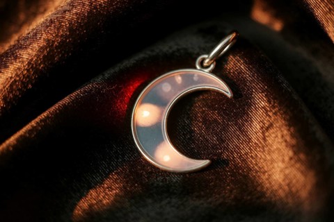 Silver crescent moon pendant on velvet, symbol of witchcraft and lunar magic. Generative ai, AI