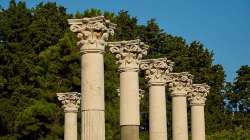 Ancient columns with ornate capitals against a backdrop of trees and clear sky, Temple of Apollo,