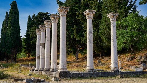 Group of ancient columns in front of a wooded landscape under a blue sky, Temple of Apollo,