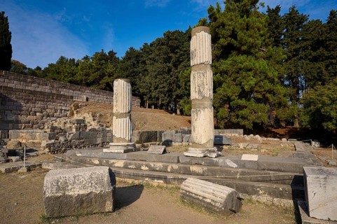 Two damaged columns stand in a historic site surrounded by trees, Asklepios Temple, Asklipion,