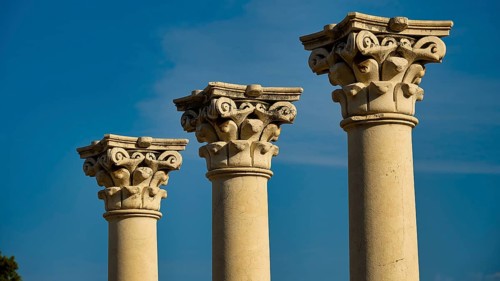 Three ancient columns with ornate capitals against a clear blue sky, Temple of Apollo, Corinthian
