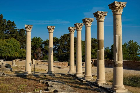 Row of ancient columns in a landscape of ruins with trees in the background, Temple of Apollo,