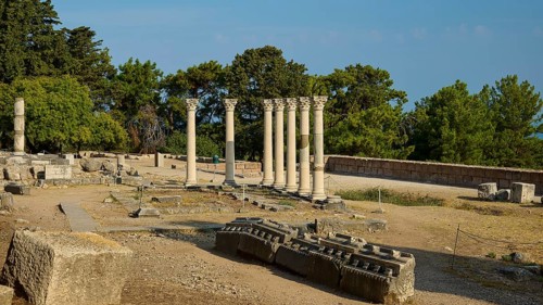 Ancient ruins with columns surrounded by lush trees in the sunshine, Temple of Apollo, Corinthian