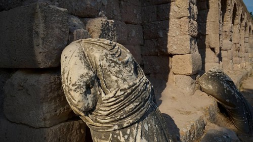 Broken ancient statue on a ruined stone wall illuminated by sunlight, ancient statue of the gods,