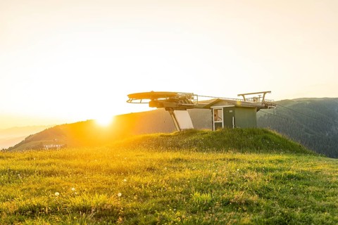 Cable car station in the evening sun with green meadow and mountains in the background, Alpe di