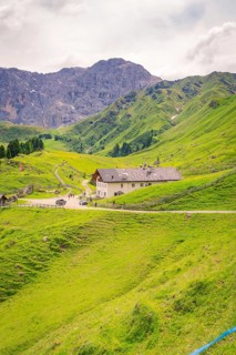 Large building nestled in a green mountain landscape under a cloudy sky, Alpe di Siusi, Dolomites,