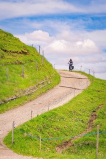 A cyclist rides on a winding hilly path in sunny weather, Alpe di Siusi, Dolomites, South Tyrol,