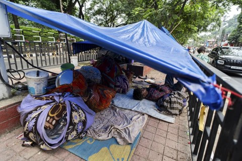A devotee takes a nap in a street divider, as he arrives to visit Kamakhya Temple during Ambubachi