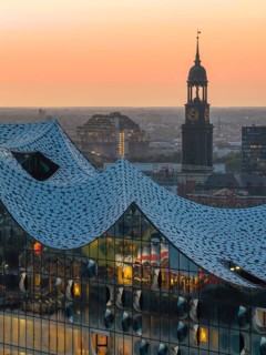 Aerial view of the Elbphilharmonie at sunset with illuminated windows and view over Hamburg and the