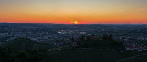 Panoramic view of a city at sunset with vineyards in the foreground and orange sky, Grabkapelle,