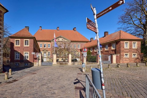 Cathedral administration, brick building, bollards, cobblestone pavement, signpost to