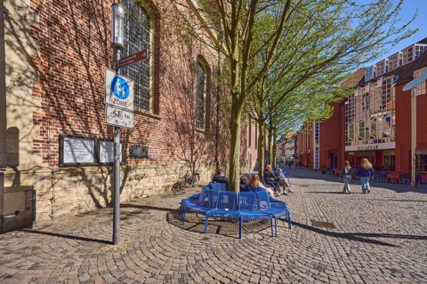 Pedestrian zone, traffic sign, benches, trees, brick building, facade, seated persons as secondary