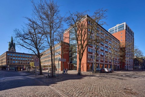 Stadthaus 1, city centre, brick building, bare wintry trees, cobblestone street, blue cloudless