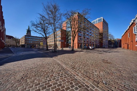Stadthaus 1, city centre, brick building, bare wintry trees, cobblestone alleyway, blue cloudless