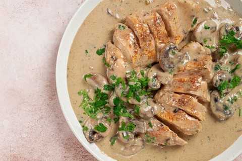 Chicken in cream sauce with mushrooms, on a plate, no people