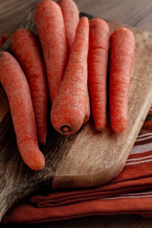 Fresh carrots on a chopping board, wooden table, raw carrots, no people