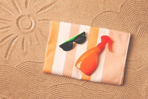 Drawing on the sand, sun and waves, sunglasses, with an orange bottle, beach towel, sun spray, on