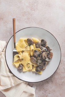 Delicious pappardelle pasta with mushrooms and cream served on a white plate