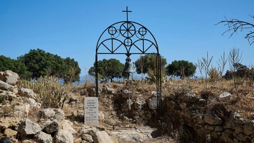 Bell tower with cross in a ruin with trees and clear sky in the background, Church of Agia