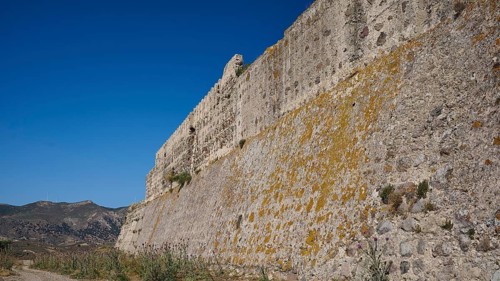 Defence wall, Fortress wall, Large stone wall with moss and vegetation under a clear sky,