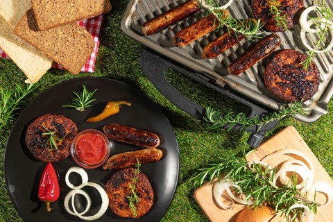 Grilled food with ketchup on a plate and grill, surrounded by bread and herbs