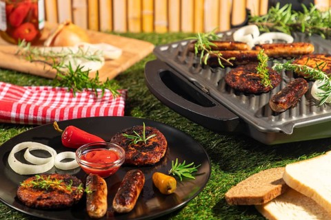 Burgers and sausages on a plate and grill with bread, rosemary and ketchup in a summery atmosphere