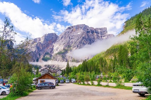Car park in front of an impressive mountain landscape with cars and buildings in the countryside,