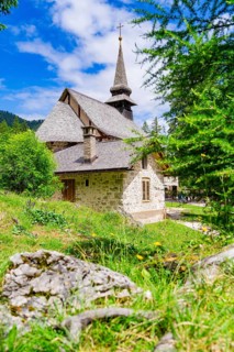 Stone church with characteristic tower in a green, sunlit landscape, Lake Braies, South Tyrol,