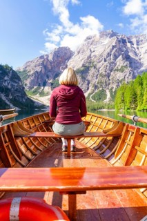 Back view of a woman in a boat on a mountain lake in sunny surroundings, Pragser Wildsee, South
