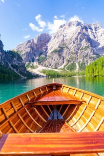 View from the boat onto a calm lake with surrounding mountain panorama under a clear sky, Lake